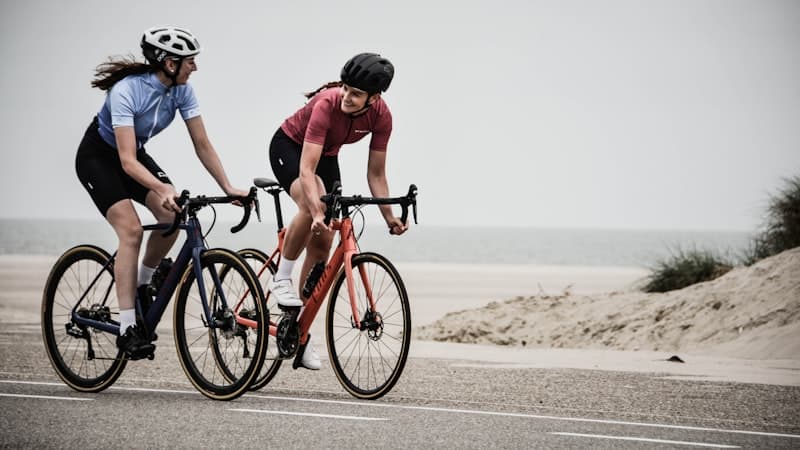 釧路湿原の緑の中をまっすぐ延びるサイクリングロードと青空